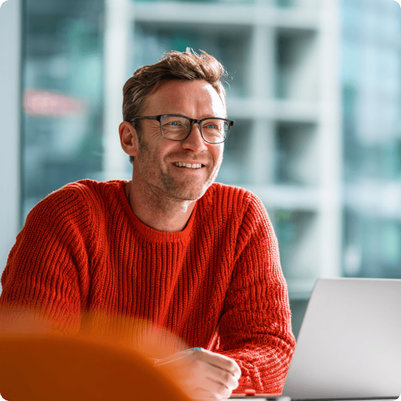 Smiling technology professional working on a laptop in a bright office