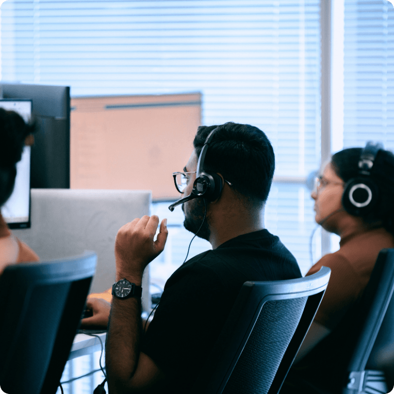 Service desk engineers wearing headsets working at their desks